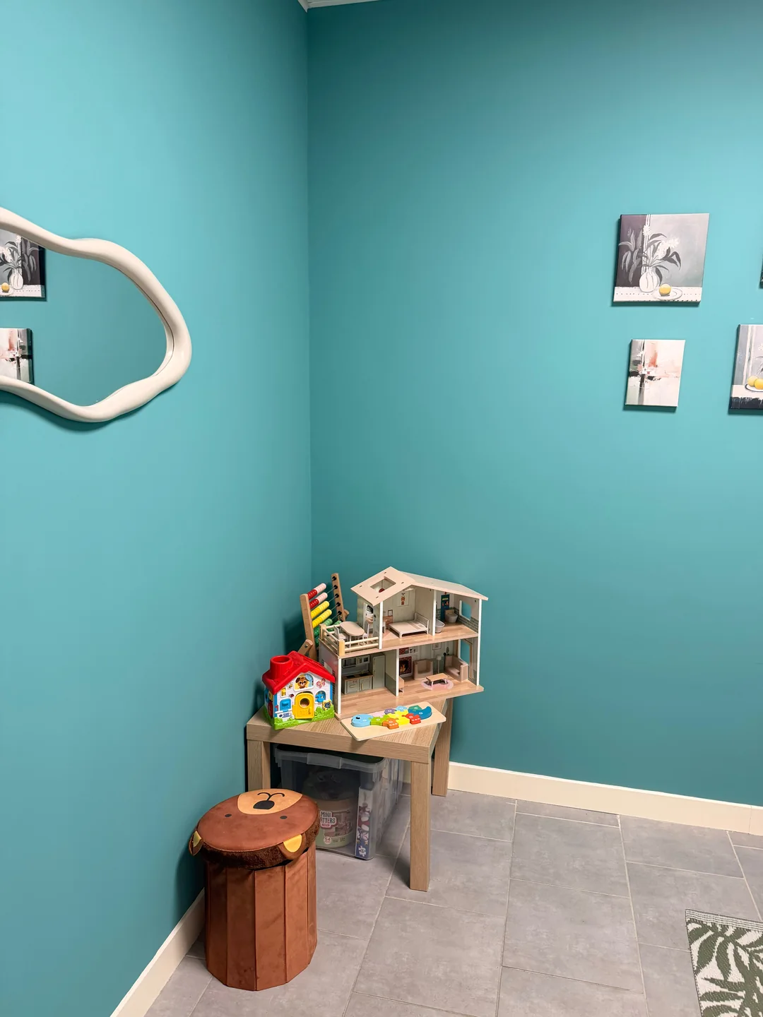 Une maison de poupées, un boulier et des jeux dans la pièce turquoise.